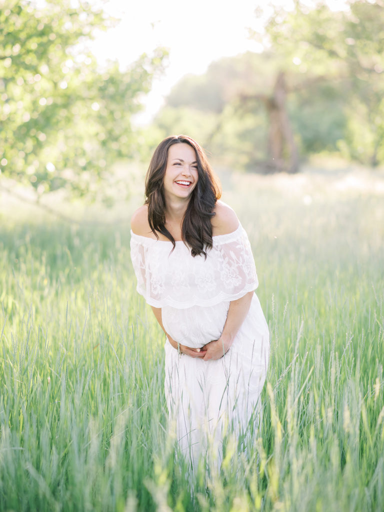 mom laughing while holding her baby belly during her Littleton maternity session